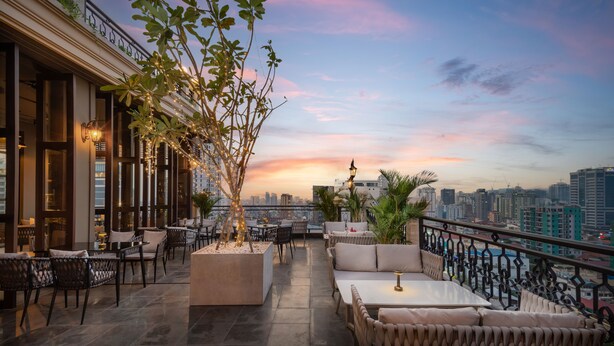 A rooftop terrace with outdoor seating, a view of the city skyline, and decorative lighting. - Duong Chan Hotel (Phnom Penh)