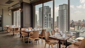 A modern restaurant with high ceilings, large windows, and a city view. - Duong Chan Hotel (Phnom Penh)