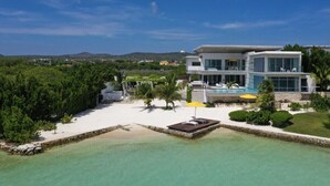 A modern two-story hotel with a pool, surrounded by lush greenery and a clear view of the landscape.