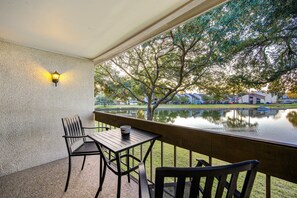 A balcony with a table and chairs, overlooking a calm water body and trees. - Serene Lakeside 2BR | Sunset Views & Relaxing Stay (Montgomery)