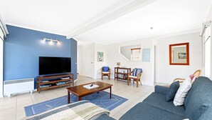 A living room with a flat-screen TV, a coffee table, a sofa, and a dining area with chairs. - 27 Harrison Street, Dalmeny (Dalmeny)