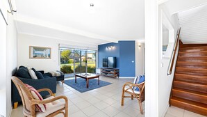 A modern living room with a sofa, chairs, a TV, and a staircase. - 27 Harrison Street, Dalmeny (Dalmeny)