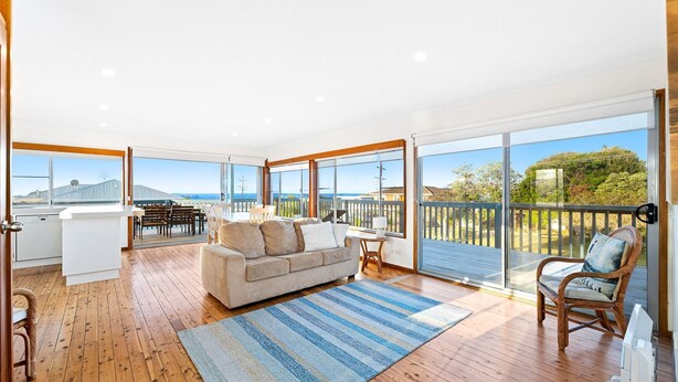 A spacious living area with a large window, a sofa, a dining table, and a kitchen area. - 27 Harrison Street, Dalmeny (Dalmeny)