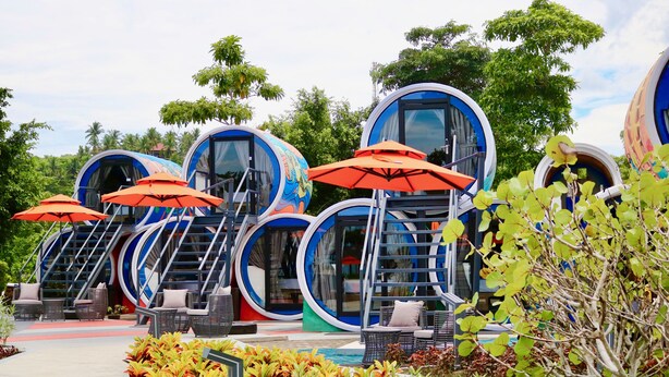 A series of circular, modern-style accommodations with outdoor seating and umbrellas. - Cocoons Club Laiya (San Juan)