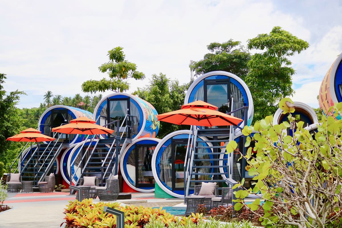 A series of circular, modern-style accommodations with outdoor seating and umbrellas.