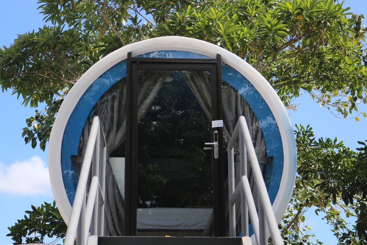 A circular structure with a door and steps leading up to it, surrounded by trees.