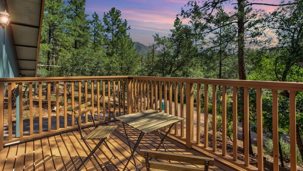A wooden deck with a bench, surrounded by trees and a view of a mountain range. - Elkchanted Inn Pine: Fully Fenced Backyard, Spacious Cabin in Woods w/King Bed (Pine)