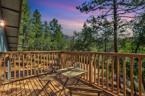A wooden deck with a bench, surrounded by trees and a view of a mountain range. - Elkchanted Inn Pine: Fully Fenced Backyard, Spacious Cabin in Woods w/King Bed (Pine)