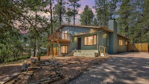 A two-story house with a balcony, a stone pathway, and a wooden fence. - Elkchanted Inn Pine: Fully Fenced Backyard, Spacious Cabin in Woods w/King Bed (Pine)