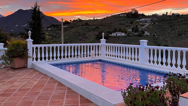 A swimming pool with a white balustrade, surrounded by terracotta tiles, overlooking a hilly landscape with a sunset sky. - Holiday Home "Cortijo Pura Vida" with Mountain View, Pool, Terrace & Garden (Cómpeta)
