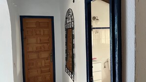 A wooden door with a geometric pattern, a decorative metal mirror, and a bathroom visible through an open doorway. - Holiday Home "Cortijo Pura Vida" with Mountain View, Pool, Terrace & Garden (Cómpeta)