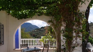 A patio with a table and chairs, a white railing, and a view of a mountainous landscape. - Holiday Home "Cortijo Pura Vida" with Mountain View, Pool, Terrace & Garden (Cómpeta)