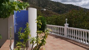 A terrace with a white balustrade, a blue tiled wall, and a view of a hillside. - Holiday Home "Cortijo Pura Vida" with Mountain View, Pool, Terrace & Garden (Cómpeta)