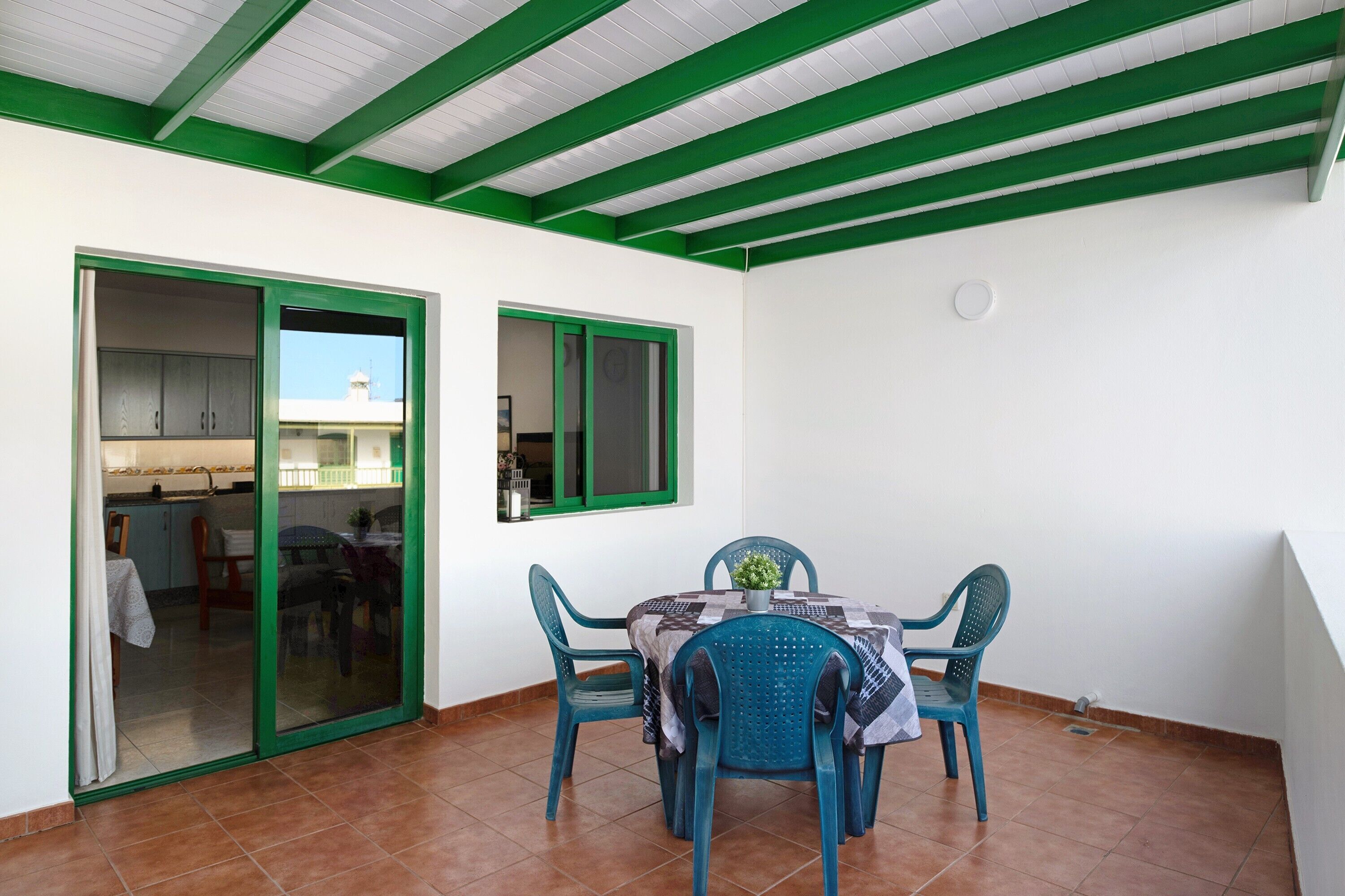 A dining area with a table and chairs, a sliding glass door, and a green-framed window.