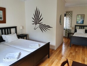 A hotel room with a bed, a nightstand, a wall decal, a window with curtains, and a painting on the wall. - Saga Hotell AB (Borlange)