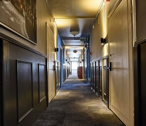 A hotel corridor with doors on both sides, a carpeted floor, and a ceiling with recessed lighting. - Saga Hotell AB (Borlange)