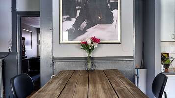 Un comedor con una mesa de madera, sillas, un cuadro en la pared y un jarrón con flores.
