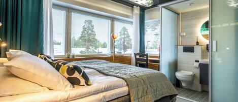 Quarto moderno com cama, escrivaninha e banheiro.