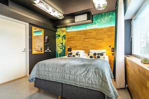 Un dormitorio moderno con una cama grande, un cabecero de madera, un espejo y una pared con un mural verde y amarillo.