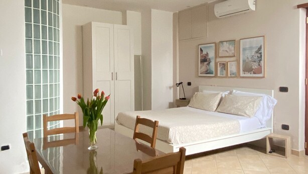 Un dormitorio con cama, una mesita de noche y aire acondicionado instalado en la pared.