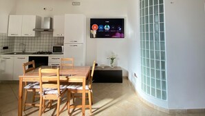 Una cocina moderna con armarios blancos, microondas y un comedor con mesa y sillas de madera.