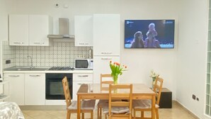 Una cocina moderna con armarios blancos, un microondas y un televisor montado en la pared.