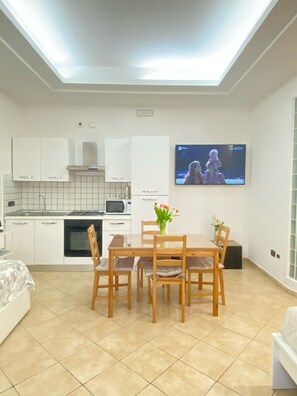Eine moderne Küche mit weißen Schränken, einer Mikrowelle und einem an der Wand befestigten Fernseher.