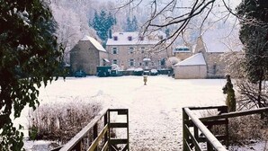 A snow-covered courtyard with a wooden bridge leading to a building.