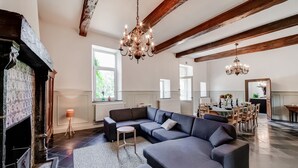A spacious living room with a large sectional sofa, a fireplace, and a dining area with wooden furniture.