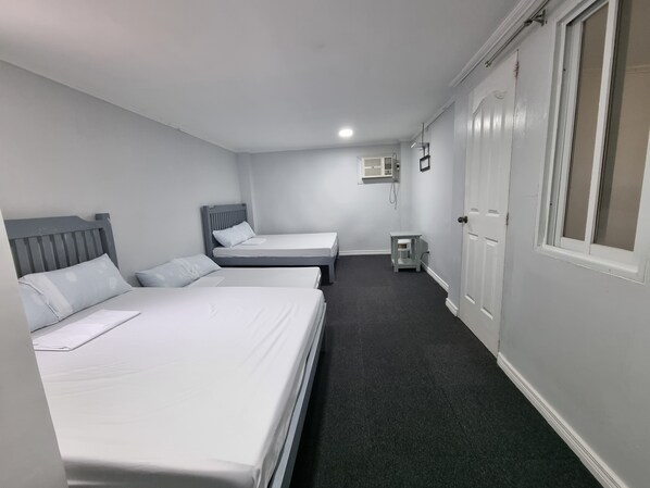 A hotel room with two single beds, a small table, a heater, and a window. - Laiya Riviera by Yemaya powered by Cocotel (San Juan)