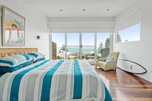 Une chambre à coucher moderne avec un grand lit, un fauteuil et une vue sur l’extérieur.