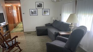 A living room with a sectional sofa, a rocking chair, a lamp, and framed pictures on the wall. - Pap's Place (Rockwood)