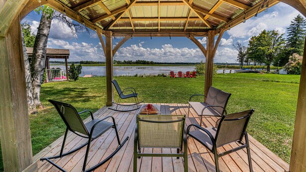Una terraza de madera con un mirador, sillas y vistas a un lago.