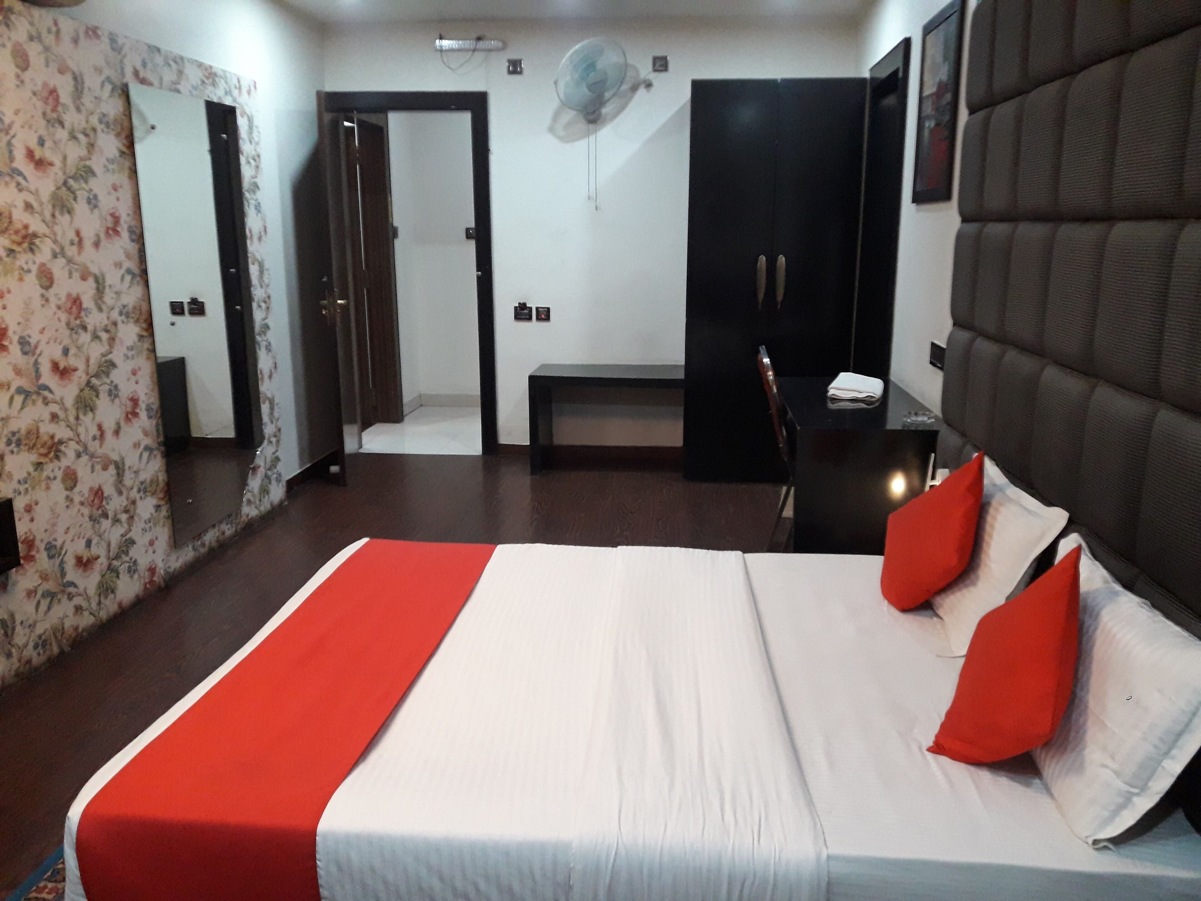 Una camera d'albergo con un letto, una panca, un armadio e uno specchio.