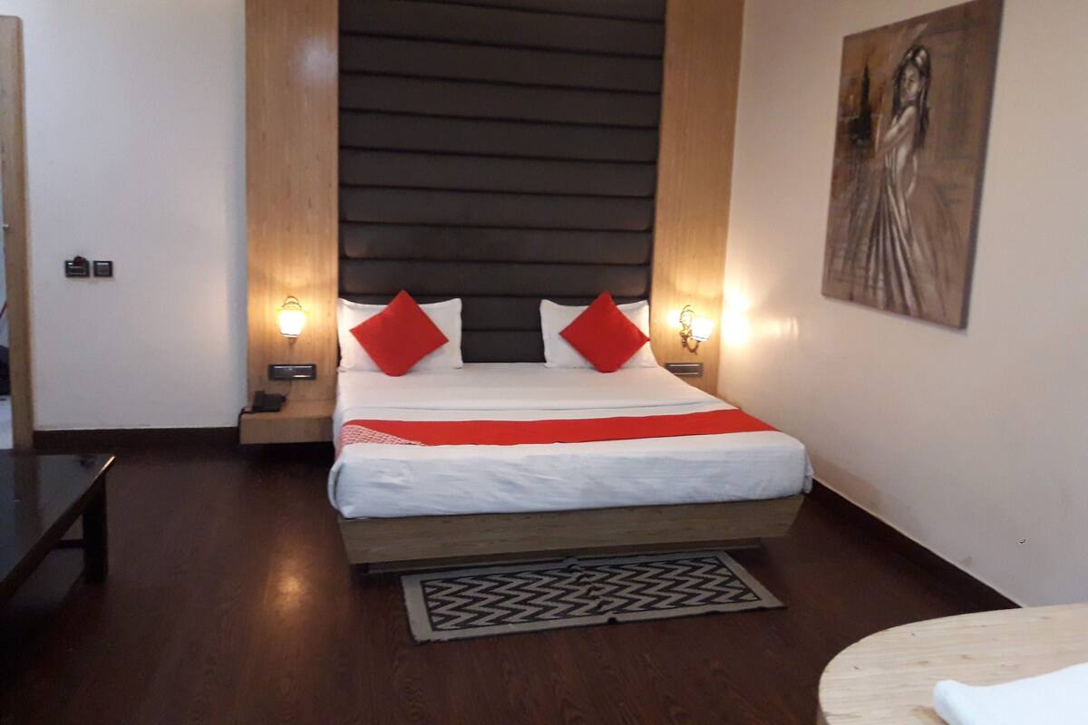 Een hotelkamer met een bed, nachtkastjes, een schilderij aan de muur en een houten vloer.