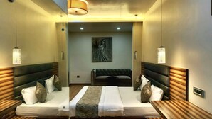 Une chambre d’hôtel moderne avec un grand lit, deux tables de chevet et un coin salon avec un canapé.