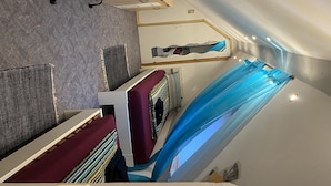 Un intérieur moderne avec un plafond en pente, un grand miroir et un tissu bleu drapé sur le mur.