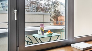 Una habitación moderna con puerta de cristal corredera, una mesita con un frutero, un vaso de agua y un jarrón decorativo.