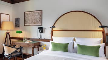 A hotel room with a bed, desk, chair, lamp, and a wall-mounted telephone.