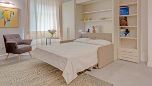 A modern bedroom with a bed, a chair, a desk, and a bookshelf. - Right House Sur Le Port (CAGLIARI)