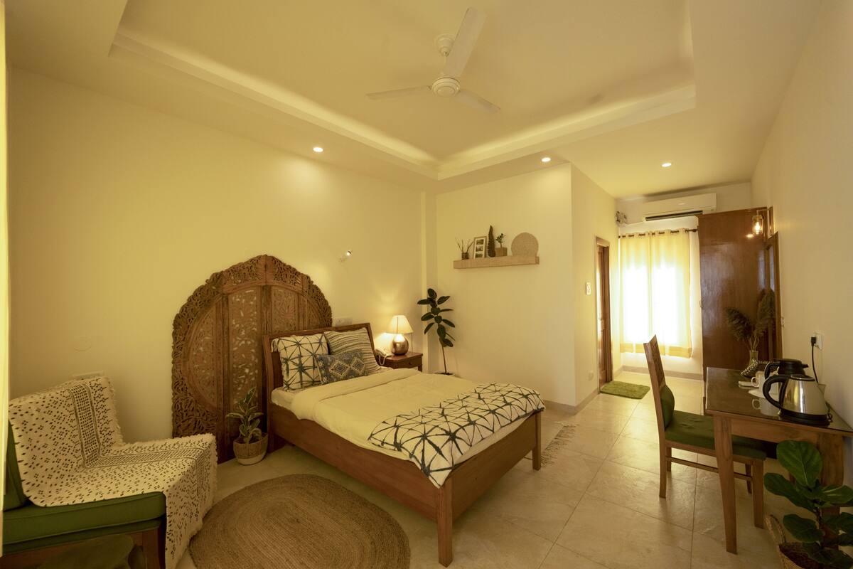 A bedroom with a bed, bedside table, lamp, and a chair.