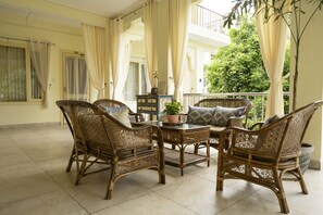 A balcony with wicker furniture, a potted plant, and a view of a green tree. - Maharishi Ayurveda Boutique Wellness Retreat (Narendranagar)