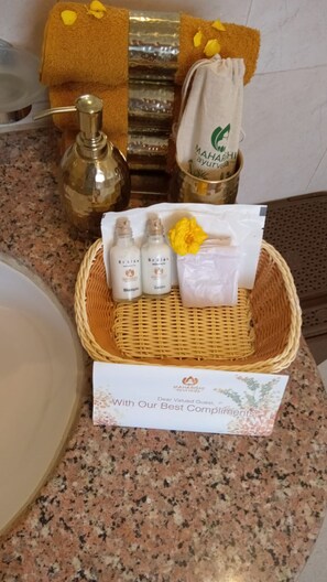 A basket with toiletries, a bottle, and a towel on a granite countertop. - Maharishi Ayurveda Boutique Wellness Retreat (Narendranagar)
