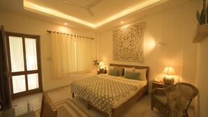 Une chambre à coucher comprenant un lit, des tables de chevet, une chaise, un ventilateur de plafond et un élément décoratif mural.