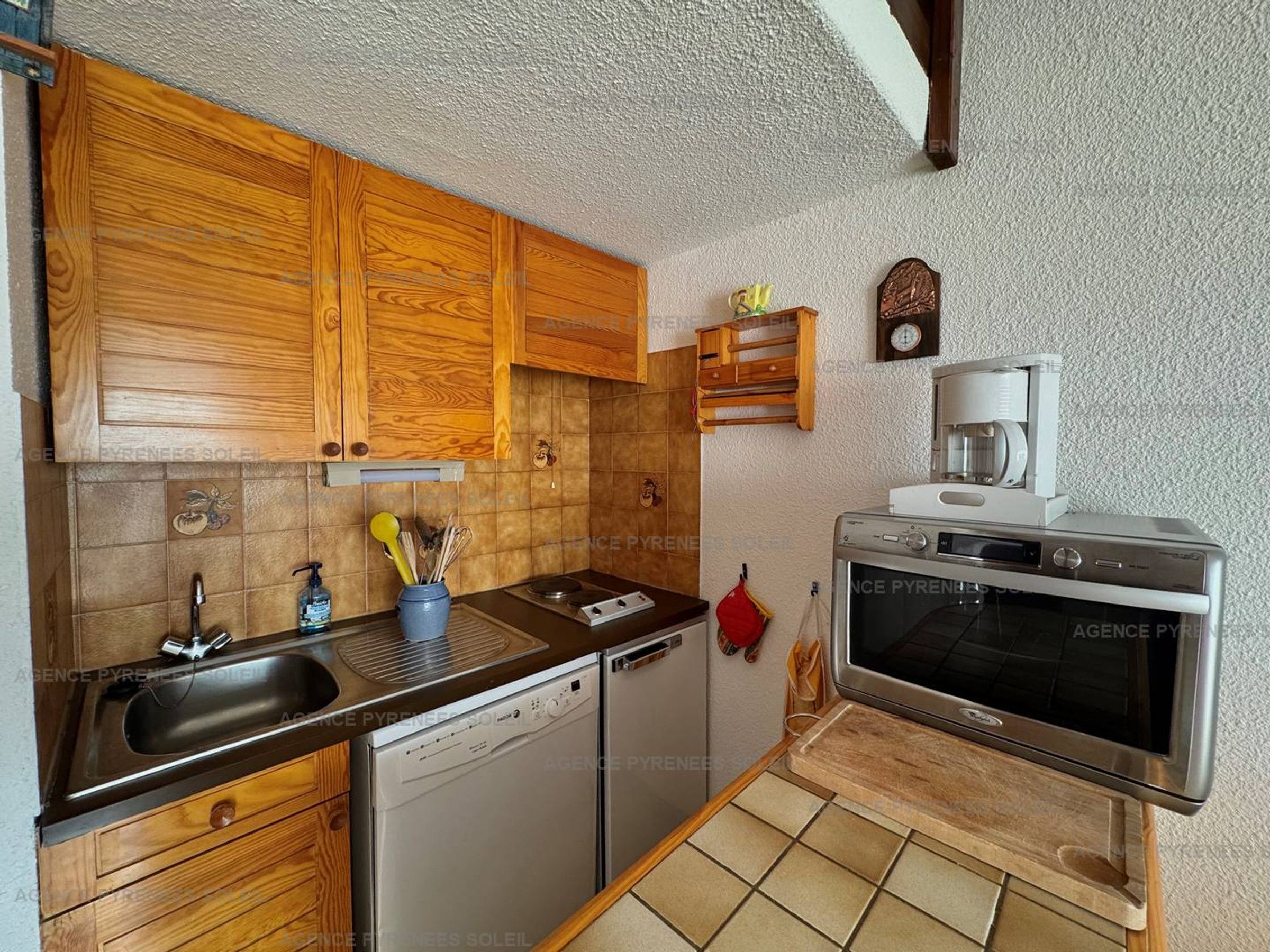 Una cocina con armarios de madera, lavavajillas, horno y cafetera.