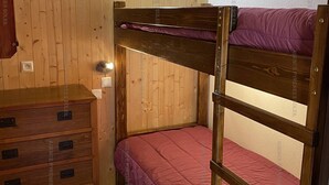 A bunk bed with a wooden frame and a pink mattress, a wooden dresser with drawers, and a wall-mounted light fixture. - Cozy 2* Apt, Ski-In/Out, Sleeps 4, Balcony, Parking, Near Hot Springs (Les Angles)