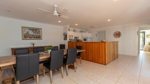Une cuisine moderne avec des meubles blancs, un îlot central en bois et un coin repas comprenant une table et des chaises en bois.