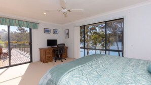 Une chambre dotée d’un grand lit, d’un bureau avec un ordinateur et offrant une vue sur l’extérieur grâce à de grandes fenêtres.