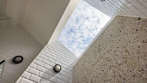 Ein modernes Badezimmer mit weiß gefliestem Boden, einer Marmorwand und einem Oberlicht.