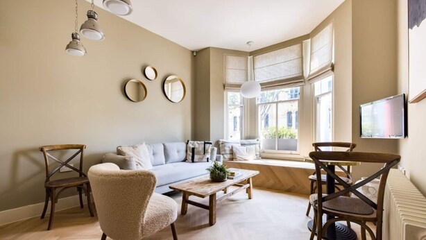 Un salon comprenant un canapé, des fauteuils, une table basse et un téléviseur fixé au mur.